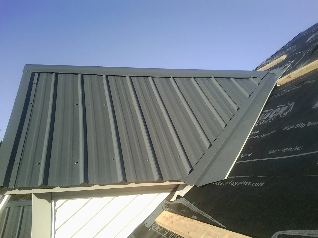 Gray metal roof panels going on over a garage gable in Scipio Center