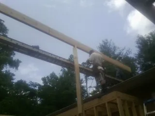 Carpenter setting a ridge beam over a new addition frame — Ice Dam Removal by Roofing Brothers in Scipio Center