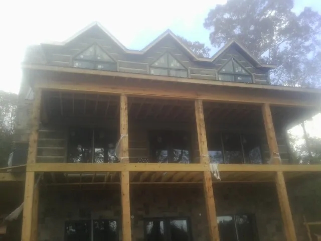 Dormers and porch framing on a large log home under construction — Roof Coating work by our crew in Scipio Center