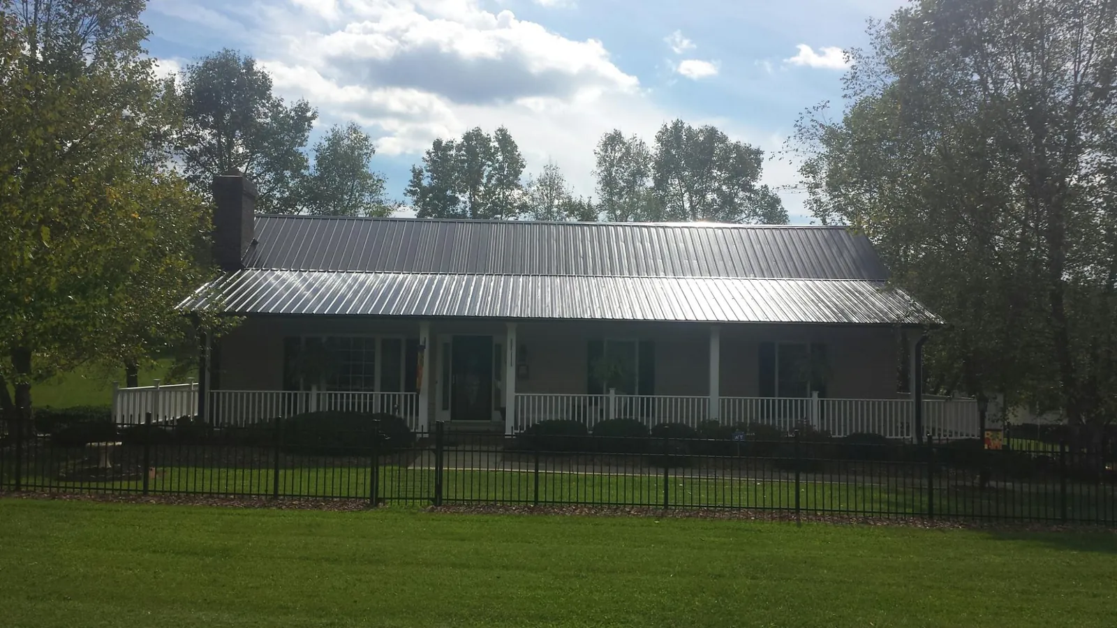 Gray metal roof on a brick ranch with a full width front porch — Gutter Guard Installation work by our crew in Scipio Center